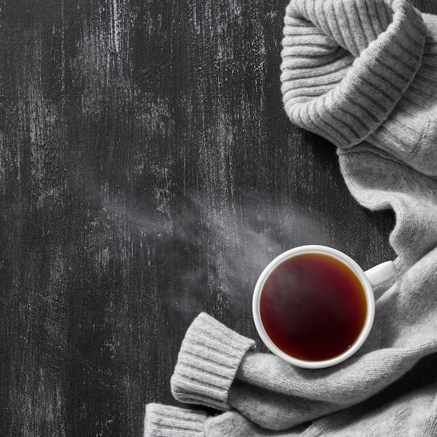 Vue de dessus image de pull tricoté confortable gris avec une tasse de café sur une table noire en bois