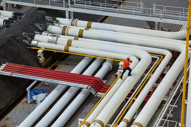 Vue de dessus inspection des travailleurs masculins dans les longs tuyaux en acier et le coude de tuyau dans l'usine de pétrole de la station pendant la vanne de raffinerie de l'huile de pipeline d'enregistrement de contrôle visuel
