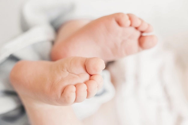 Vue De Dessus De Jambes De Bébé Nouveau-né Deux Pieds De Bébé Sur Le Fond De Linge De Lit Blanc