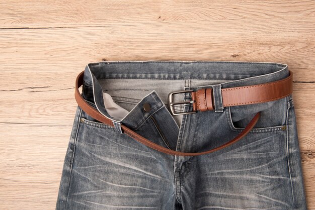 Photo vue de dessus jeans et ceinture de cuir rythme sur fond de bois.