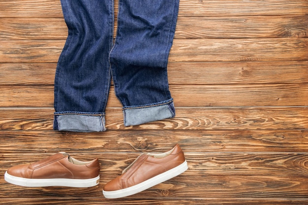 Vue de dessus des jeans et des chaussures marron sur fond de bois