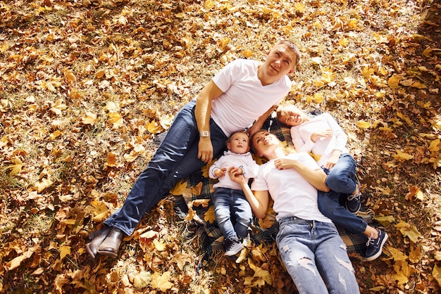 Vue de dessus d'une jeune famille joyeuse qui se repose ensemble dans un parc d'automne.