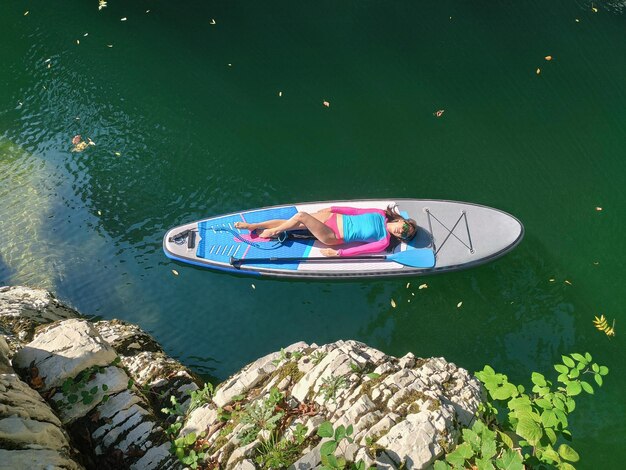 Vue de dessus d'une jeune femme allongée et relaxante sur le SUP dans le canyon au fond de l'eau