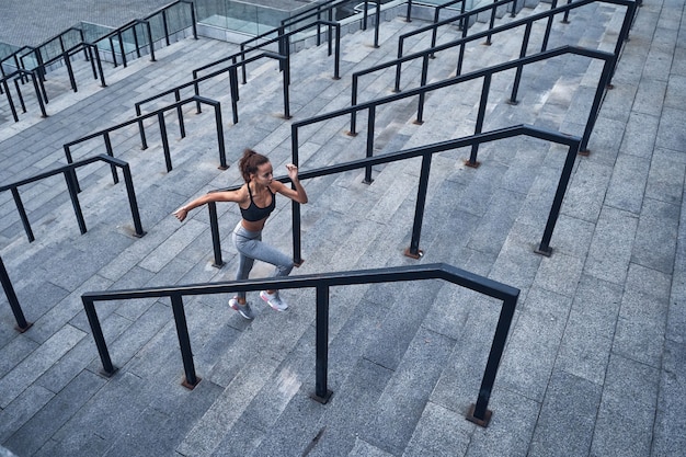 Photo vue de dessus d'une jeune femme athlétique courant à l'étage entraînement rapide au stade de la ville urbaine