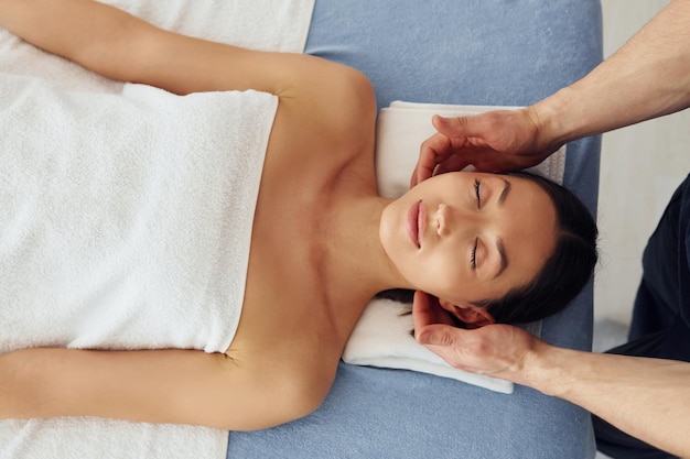 Vue de dessus Une jeune femme est allongée quand un homme fait un massage de son corps au spa
