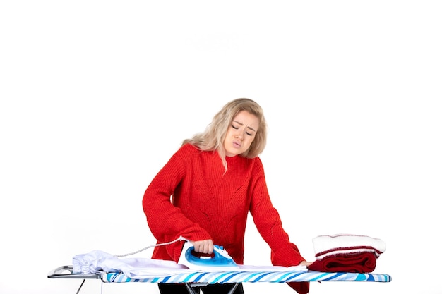 Vue de dessus de la jeune femme malheureuse belle repassage des vêtements sur fond blanc