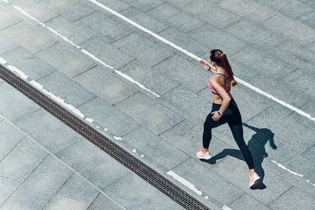 Vue de dessus d'une jeune femme séduisante en vêtements de sport courant à l'extérieur