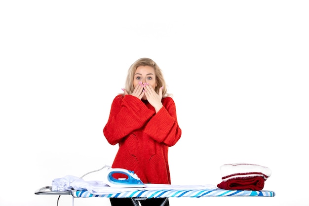 Vue de dessus d'une jeune femme souriante et choquée en train de repasser des vêtements sur fond blanc