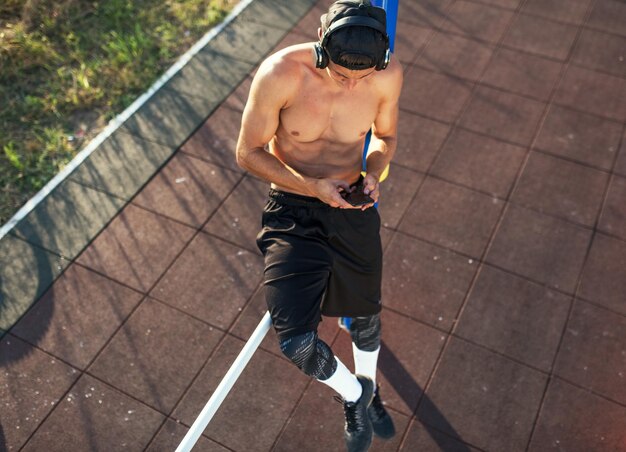 Photo vue de dessus d'un jeune homme musclé athlétique se détendre après l'entraînement sur le terrain d'entraînement à l'extérieur