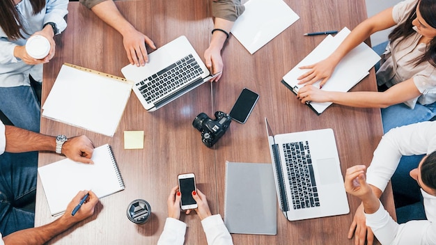 Vue de dessus de jeunes gens d'affaires qui travaillent avec des documents et un ordinateur portable dans le bureau moderne.