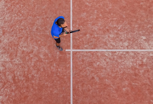 Vue de dessus d'un joueur de paddle-tennis attendant la balle dans un match sur un terrain extérieur.