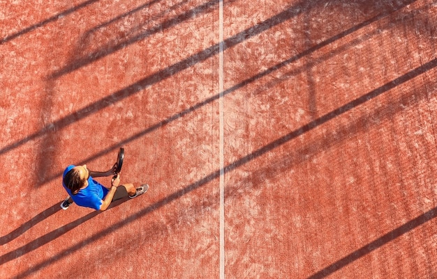 Vue de dessus d'un joueur de paddle-tennis professionnel tenant la raquette lors d'un match sur un terrain extérieur.