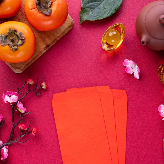 Vue de dessus des kakis frais et sucrés avec des feuilles sur fond de table rouge pour le concept de conception de fruits du nouvel an lunaire chinois, le mot signifie que le printemps arrive.