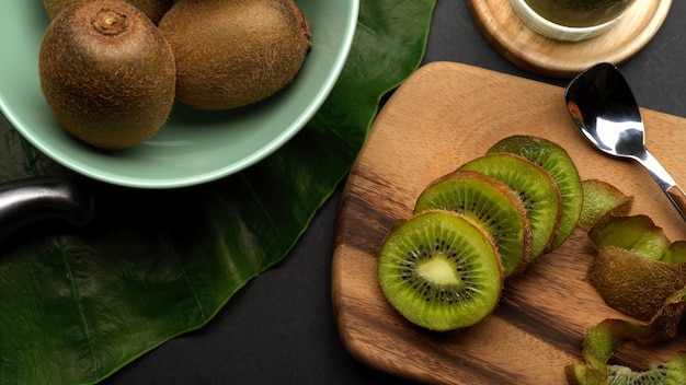 Vue de dessus de kiwis entiers et tranchés sur table de cuisine et fruits tropicaux