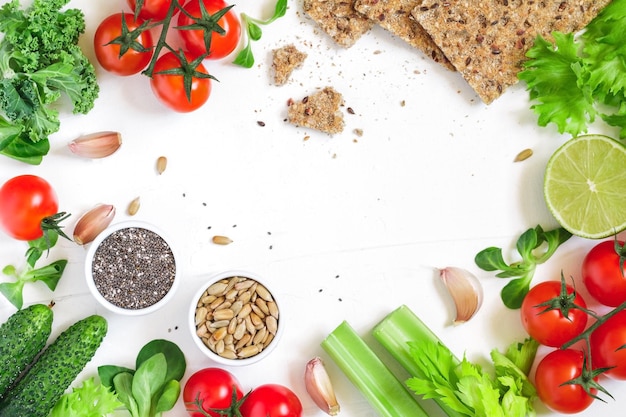 Vue de dessus des légumes frais et des pains de grains entiers sur fond blanc Cadre d'aliments sains et biologiques Mise à plat