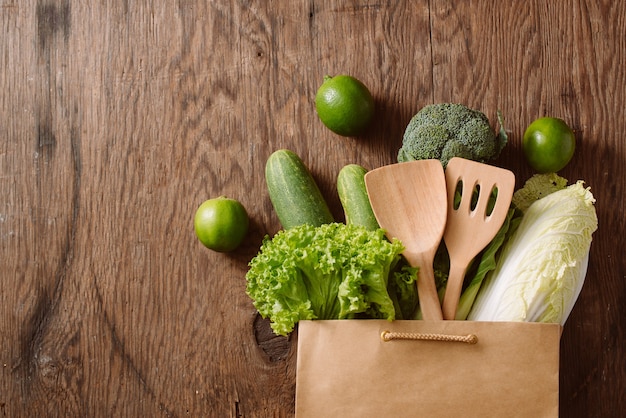 Vue de dessus des légumes verts dans un sac à provisions sur une table en bois