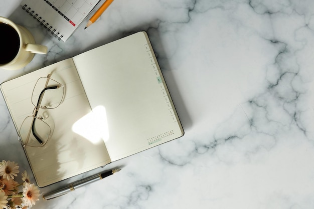 Vue de dessus des lunettes de cahier et une tasse de café sur fond de marbre