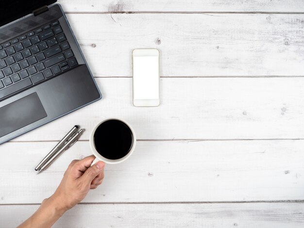 Vue de dessus des lunettes d'ordinateur portable de l'espace de travail et deux stylos en argent et un espace de copie de tasse de café à la main