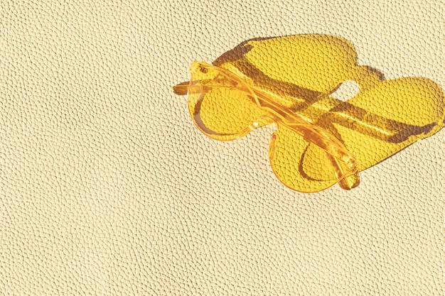 Vue de dessus sur des lunettes de soleil à la mode d'été sur un mur texturé en cuir. Vacances d'été, fête, mode, concept de voyage