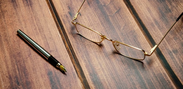 Vue de dessus des lunettes et un stylo sur le fond en bois