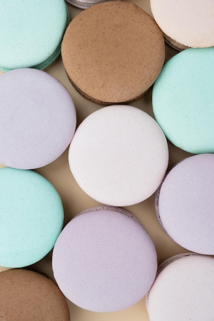 Vue de dessus de macarons de pâtisserie de différentes couleurs pastel sur fond beige Fond de nourriture sucrée