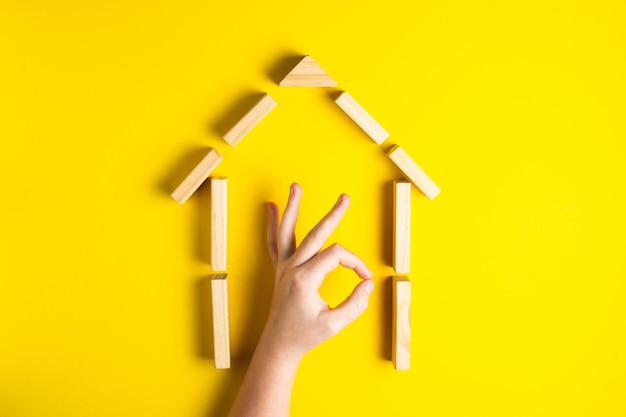 Vue de dessus de la main de l'enfant en gros plan des blocs de construction montrant ok, maison, cabane en bois