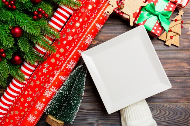 Vue de dessus d'une main féminine tenant une assiette sur la table en bois de vacances. Sapin et décorations de Noël. Cocnept du Nouvel An