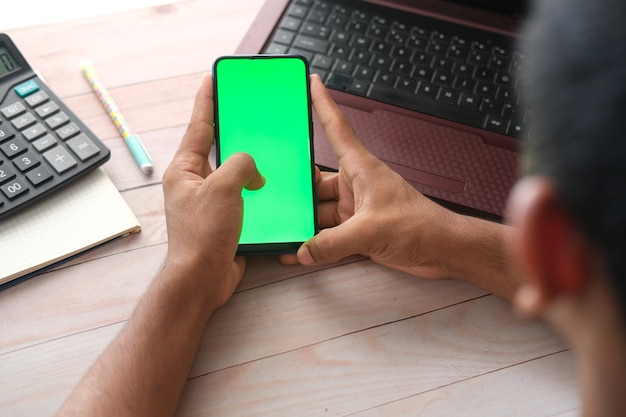 Vue de dessus de la main de l'homme à l'aide d'un téléphone intelligent sur le bureau