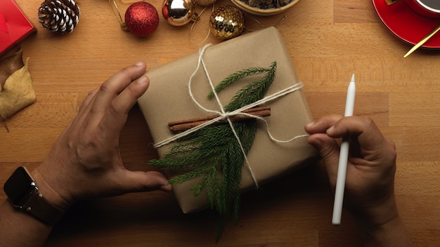Vue De Dessus De La Main Masculine Ouvrant Une Boîte Présente Sur Table En Bois Avec Des Décorations De Noël
