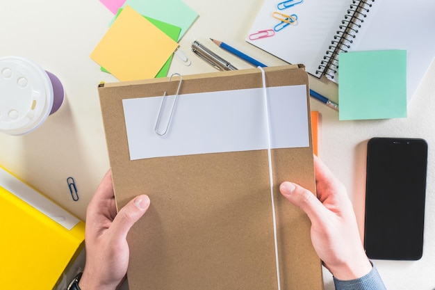 Vue de dessus d'une main masculine tenant des dossiers sur un bureau