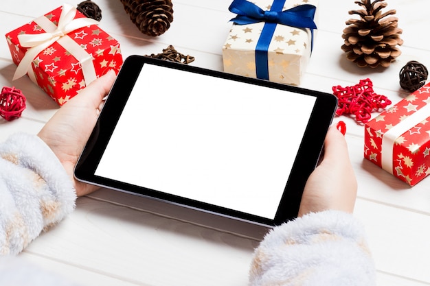 Vue de dessus des mains féminines tenant une tablette sur fond de Noël en bois