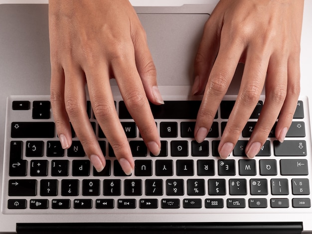 Vue de dessus des mains d'une femme en tapant sur un clavier d'ordinateur