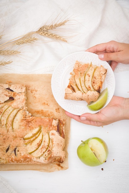 Vue de dessus sur les mains de la femme tenant une assiette avec une tarte aux pommes croustillante maison