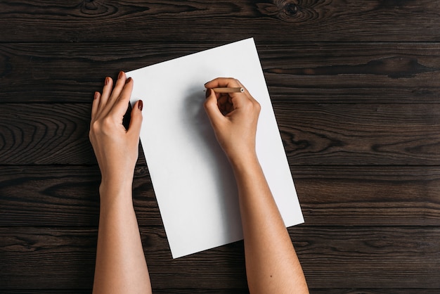 Photo vue de dessus des mains des femmes, prêt à écrire quelque chose sur un morceau de papier vide