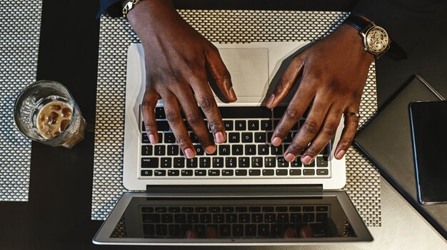 Vue de dessus des mains de l'homme tapant sur un clavier de l'ordinateur portable