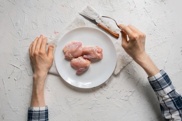 Vue de dessus des mains de la personne mangeant de la viande crue non cuite dans l'assiette