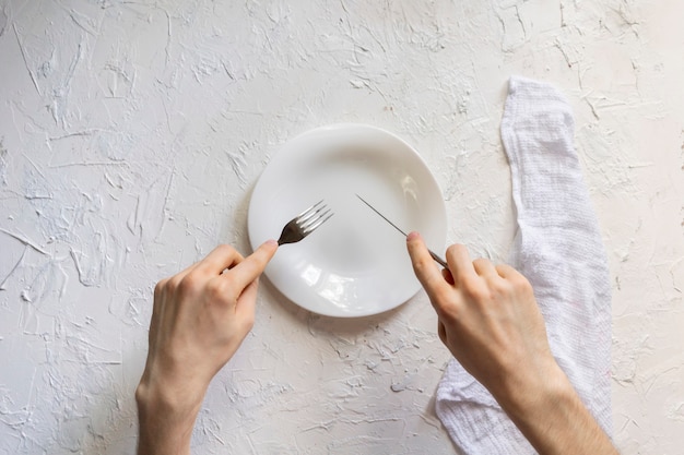 Vue de dessus des mains de la personne sur la table avec une assiette vide