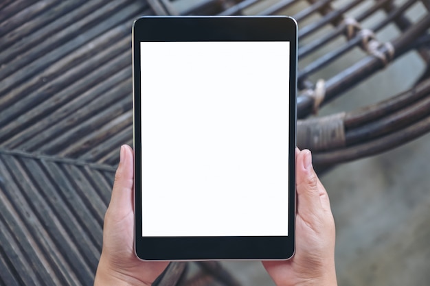 Vue de dessus mains tenant et à l'aide de tablet pc noir avec écran de bureau blanc vierge alors qu'il était assis en plein air