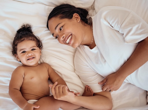 Vue de dessus maman et bébé avec le sourire sur le lit et heureux ensemble pour créer des liens d'enfance et aimer à la maison Aimer maman ou tout-petit dans le bonheur de la chambre ou positif pour le bien-être, la tendresse et la maternité