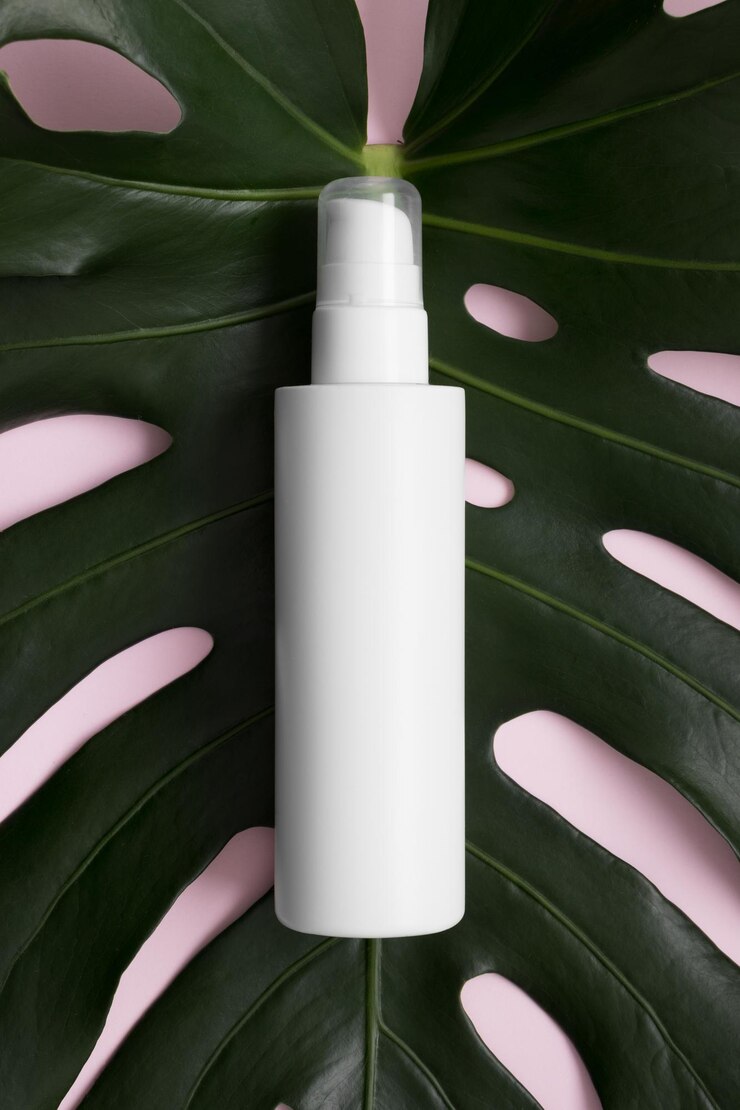Photo vue de dessus d'une maquette de bouteille de lotion cosmétique blanche avec une feuille de monstère sur fond rose