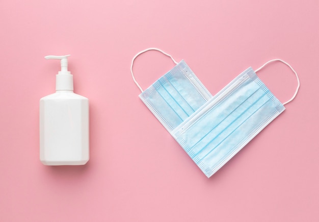 Photo vue de dessus des masques médicaux en forme de coeur avec une bouteille de savon liquide