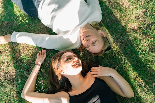 Vue de dessus de la mère et de la fille matures allongées sur l'herbe le jour d'été ensoleillé