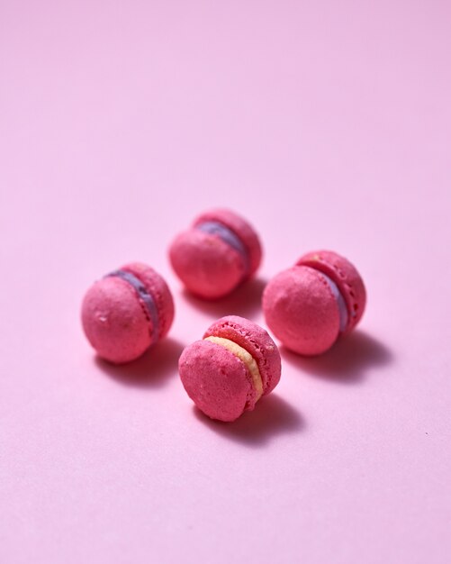 Vue de dessus de mini macarons roses sur fond de papier rose doux et doux avec un espace pour votre texte. Bonbons. Fond de nourriture.