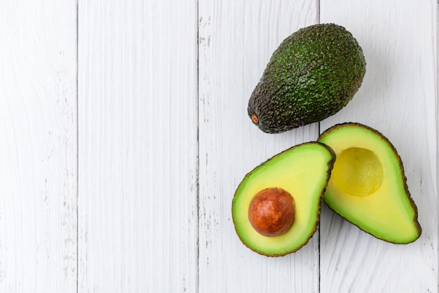 Vue de dessus de la moitié de l'avocat sur la table en bois blanc et copiez l'espace. Avocat vert frais et mûr