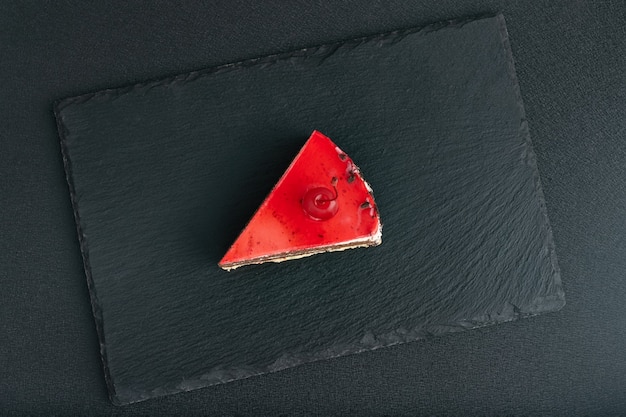 Vue de dessus sur un morceau de gâteau aux fruits rouges sur un plateau en pierre noire.