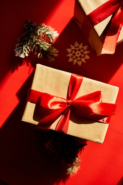 Vue de dessus Noël emballage écologique papier kraft et cadeaux de branches de sapin pour la saison des fêtes sur fond rouge, lumière dure