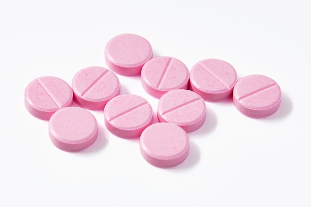 Vue de dessus de nombreuses pilules roses en forme de cercle isolées sur fond blanc