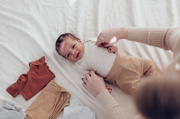 Vue de dessus d'un nouveau-né sur le lit maman porte des vêtements à son petit enfant