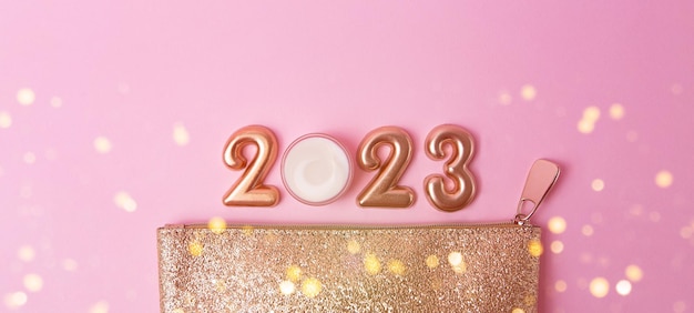 Vue de dessus des numéros d'or rose 2023 et de la crème pour le visage du sac cosmétique ci-dessus doré à proximité