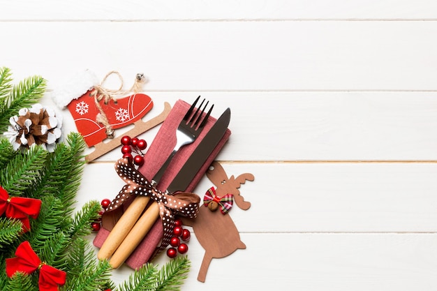 Vue de dessus des objets de vacances sur fond en bois Ustensiles attachés avec du ruban sur la serviette Décorations de Noël et rennes avec espace de copie Concept de dîner du nouvel an